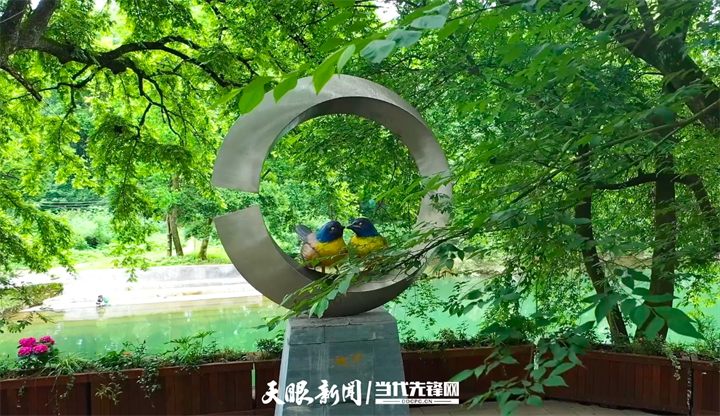 3 綠蔭林下，一座環(huán)形雕塑內(nèi)，兩只藍冠黃喉的小鳥雕像相依相偎。.png